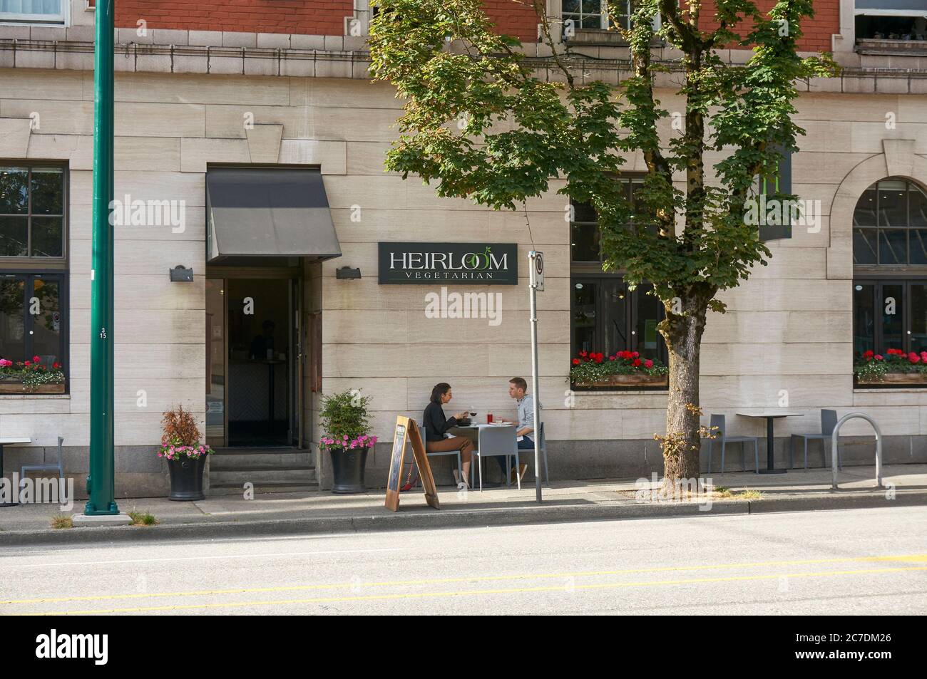 Ein junger Mann und eine Frau sitzen an einem Tisch außerhalb Heirloom vegetarisches Restaurant in Vancouver, British Columbia, Kanada Stockfoto