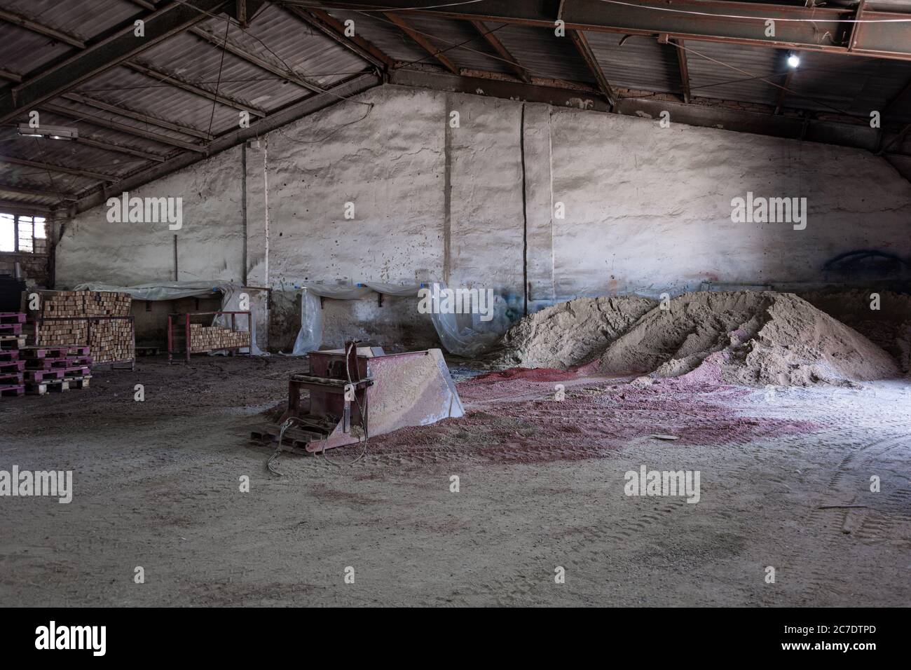 Sand und Farbe für Pflasterplatten sind auf dem Boden in der Pflastersteinproduktionswerkstatt verstreut. Stockfoto