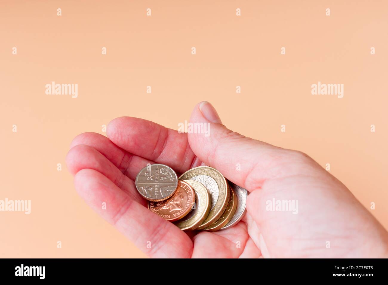 Weibliche Hand mit einigen britischen Sterling Münzen Stockfoto