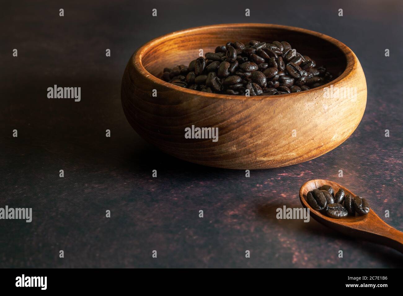 Dunkle Röstung Kaffeebohnen in einer Holzschüssel mit Holzlöffel Stockfoto