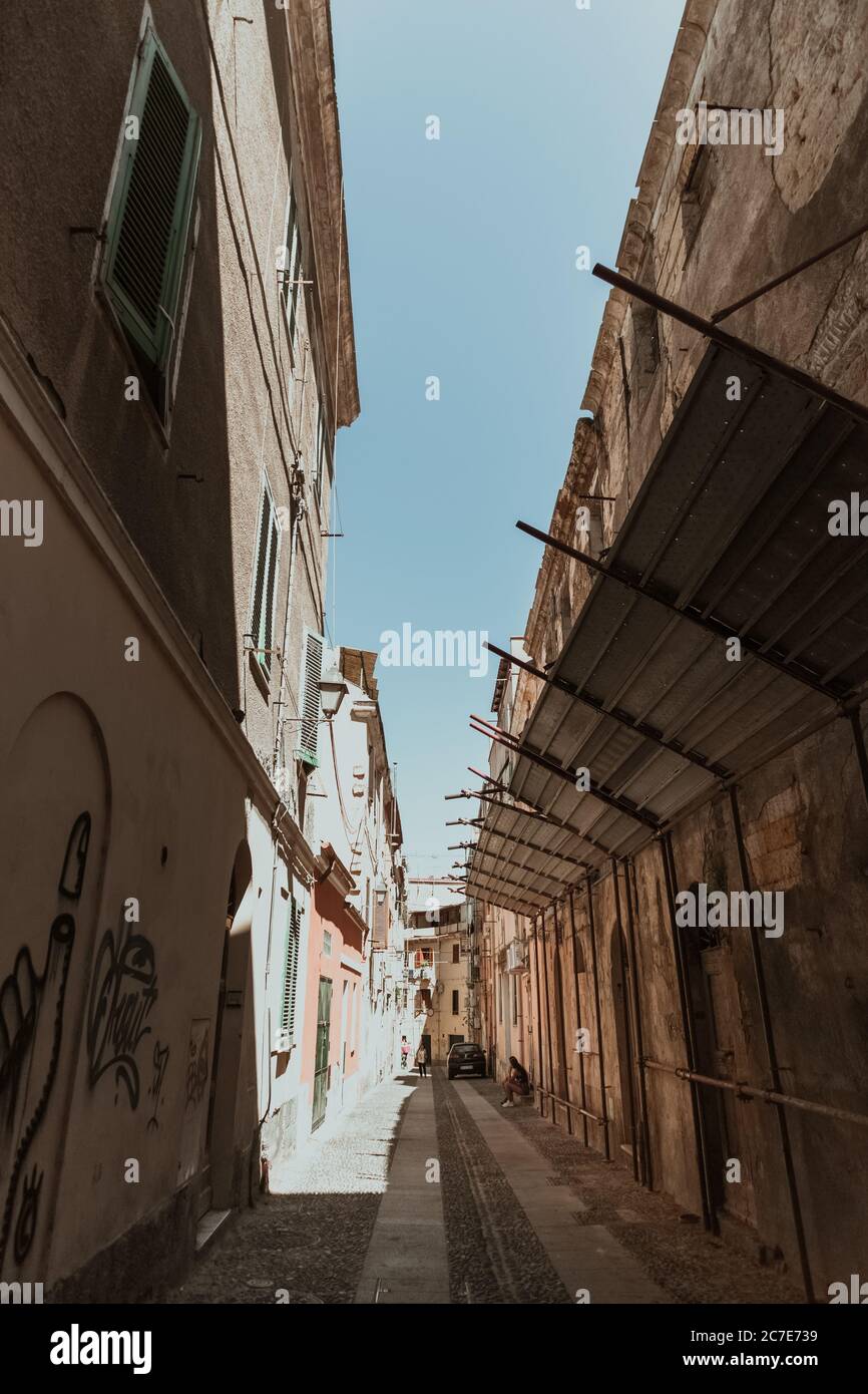 Vertikale Aufnahme einer Gasse in der Mitte von Gebäuden Unter blauem Himmel am Tag Stockfoto