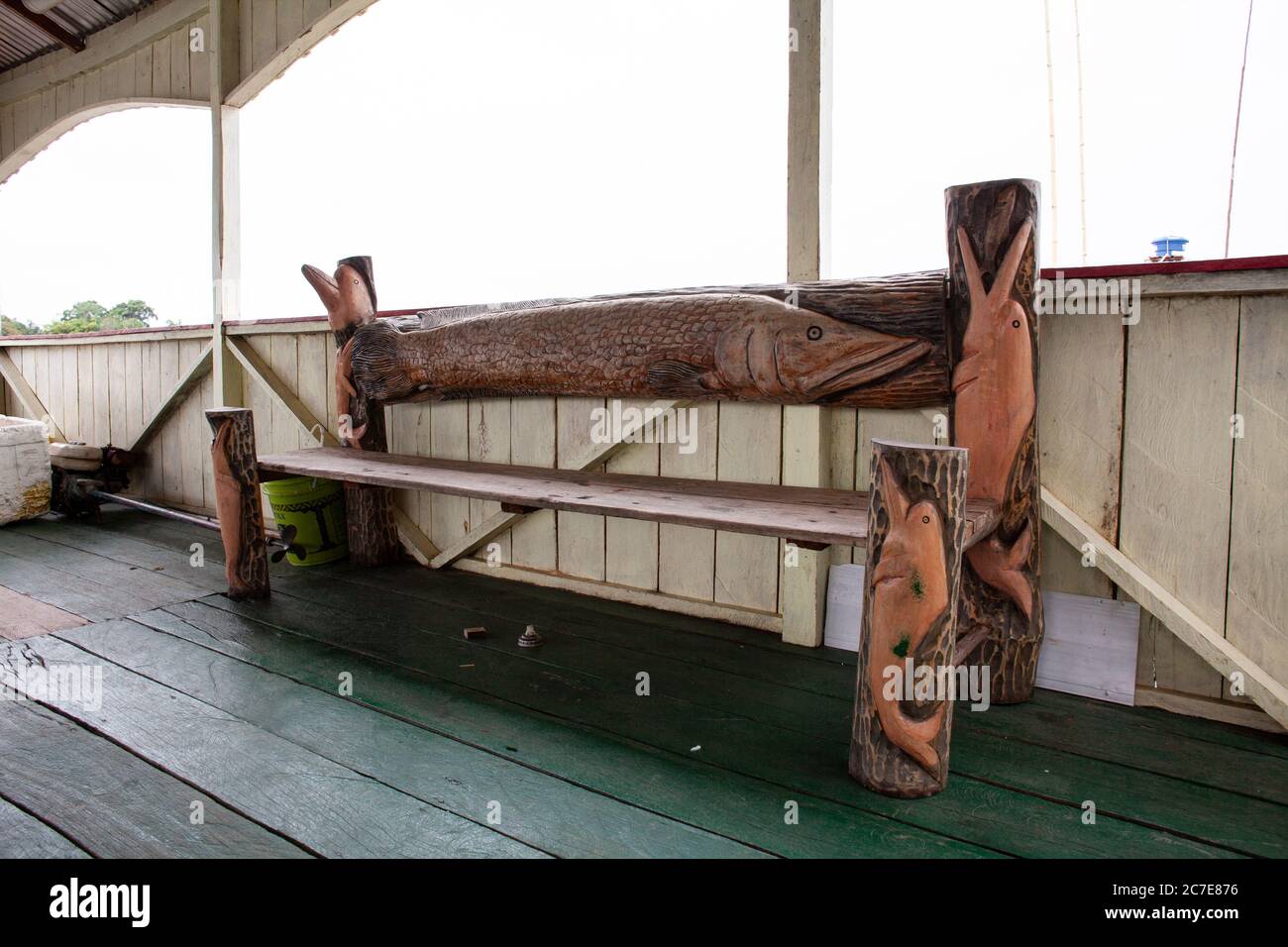 Handgeschnitzte Holzbank mit Flussdelfinen auf einer Lodge-Terrasse am Flussufer entlang des Amazonas in Brasilien Stockfoto