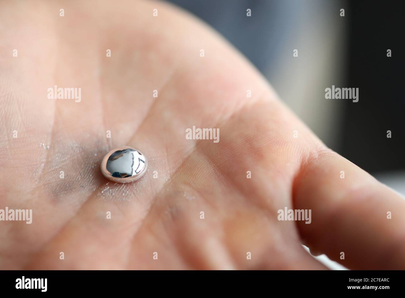 Männliche Hand hält Stück flüssiges Gallium Stockfoto