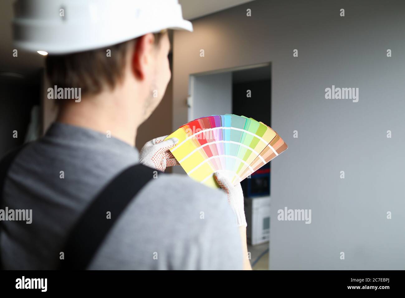 Builder in Helm hält Farbpalette in der Nähe der Wand Stockfoto