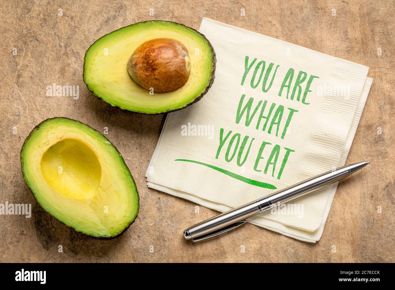 Gesundes Essen und Lifestyle-Konzept - Sie sind, was zu essen Erinnerungsworte handgeschrieben auf einer Serviette mit geschnittenen Avocado Frucht Stockfoto