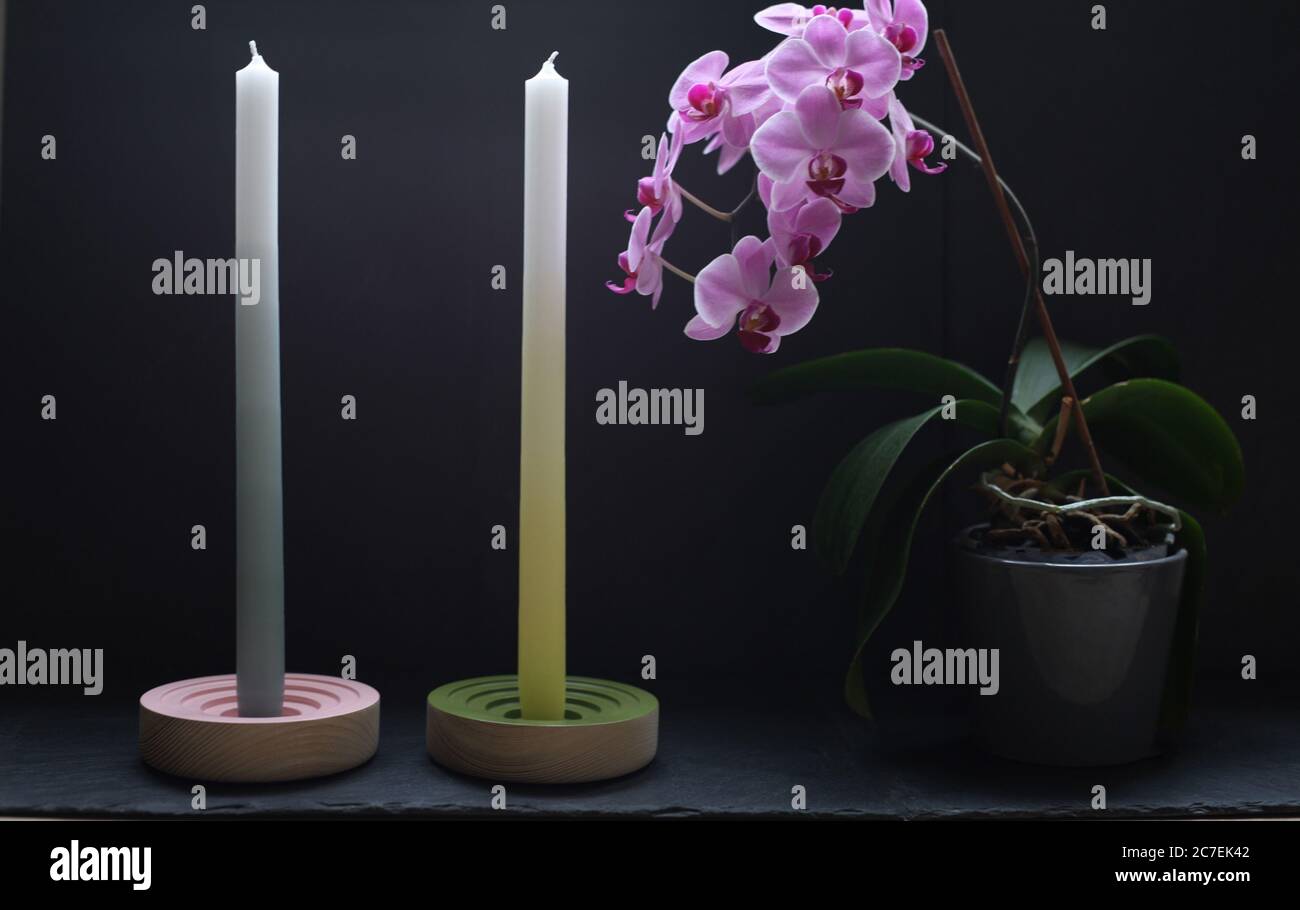 Nahaufnahme der Einrichtung von zwei Kerzen und Topfe Rosa Orchideen mit schwarzem Hintergrund Stockfoto