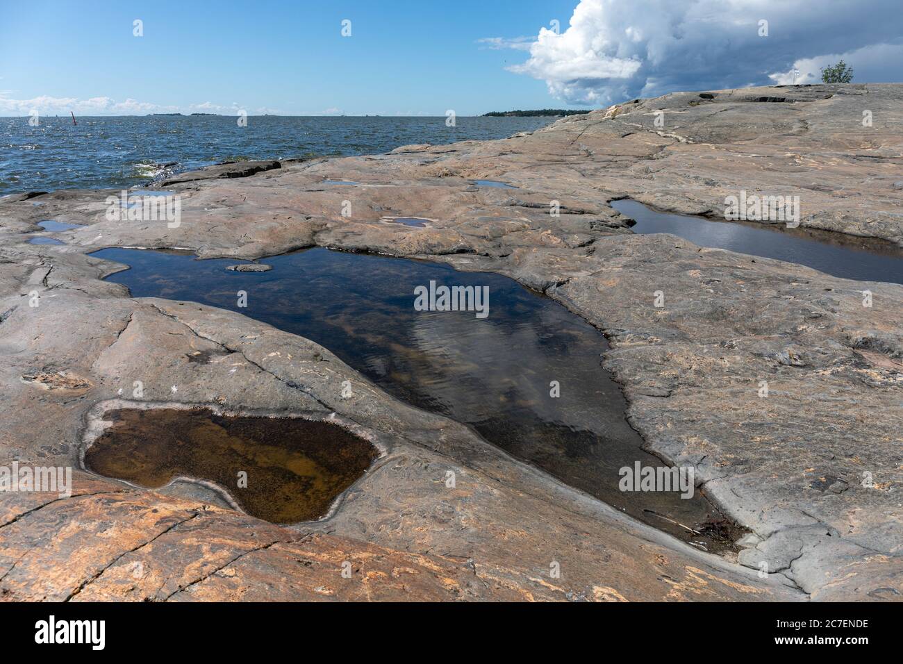 Regenwasserbecken oder Pfützen auf einem Uferfelsen in Eteläinen Uunisaari in Helsinki, Finnland Stockfoto