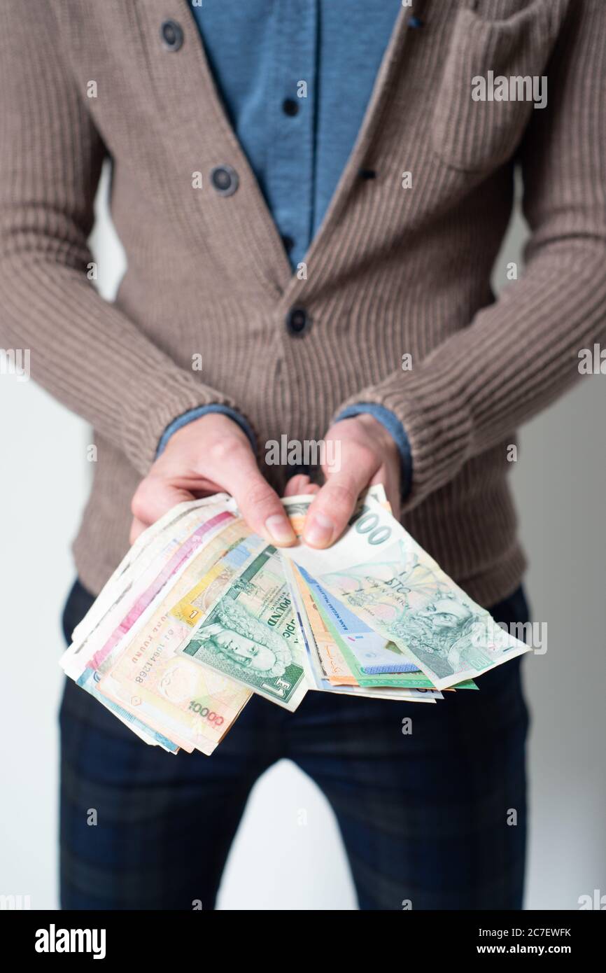 Mann, der verschiedene Währungen der Welt in Händen hält, Konzept - Geld, Bargeld, Welt, Reisender, Weltenbummler, Währung Stockfoto