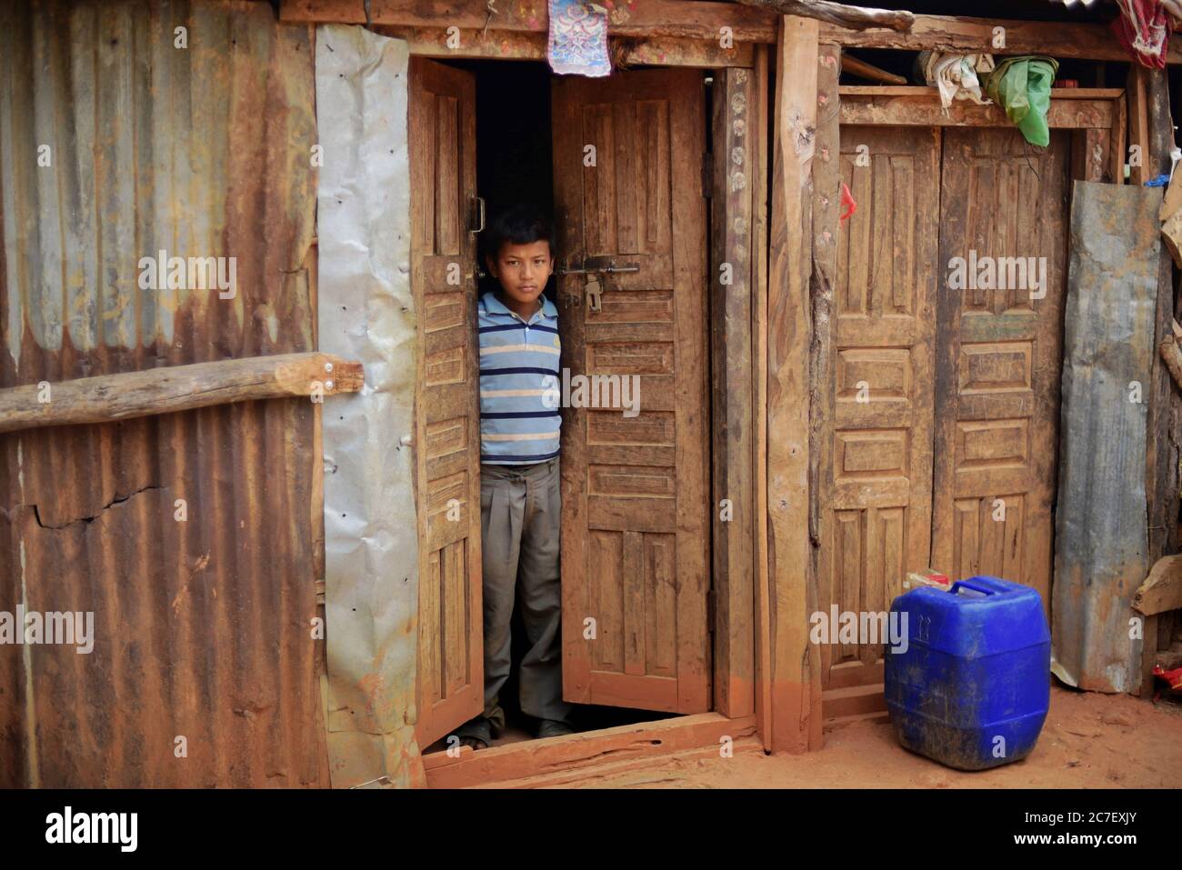 Porträt eines Jungen, der ein Jahr nach den Erdbeben und Erdrutschen 2015 in Kavrepalanchok, Bagmati Pradesh, Nepal, vor der Tür seines Hauses steht. Stockfoto