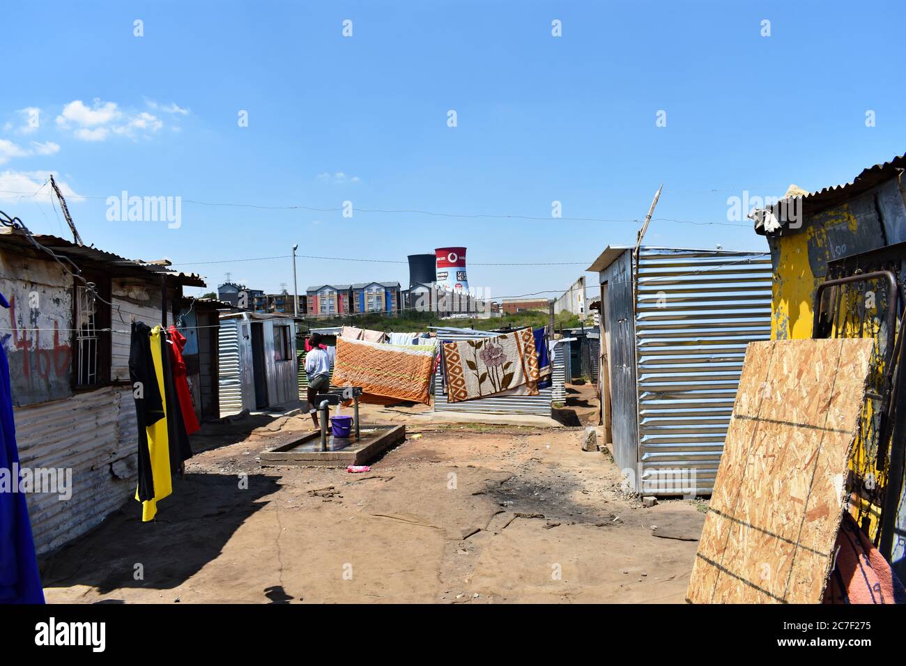 Kleidung und Bettwäsche trocknen auf der Wäscheleine in einem Slum in Soweto, Johannesburg, Südafrika. Die Orland Cooling Towers sind in der Ferne zu sehen Stockfoto