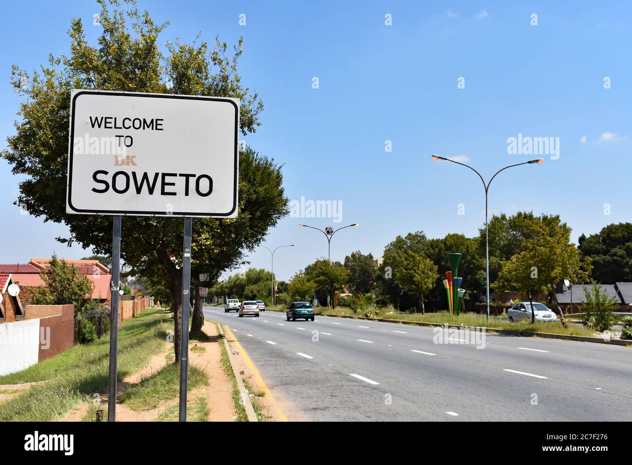 Das Welcome to Soweto Schild entlang einer der Hauptstraßen in die Gemeinde. Autos sichtbar vorbeifahren an einem klaren Tag. Johannesburg, Südafrika Stockfoto