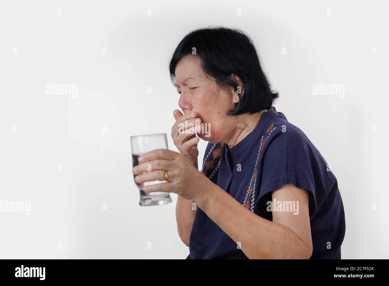 Ältere Frau erstickend ein Wassergetränk nach Einnahme Medizin, isoliert auf weißem Hintergrund. Stockfoto