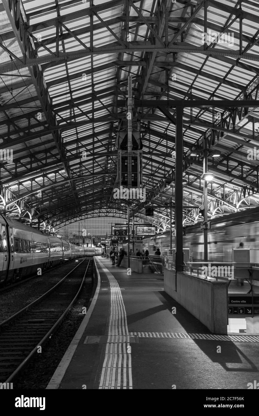 LAUSANNE, SCHWEIZ - 11. Sep 2019: Eine vertikale Aufnahme von Menschen, die auf den Zug warten, in schwarz-weiß Stockfoto