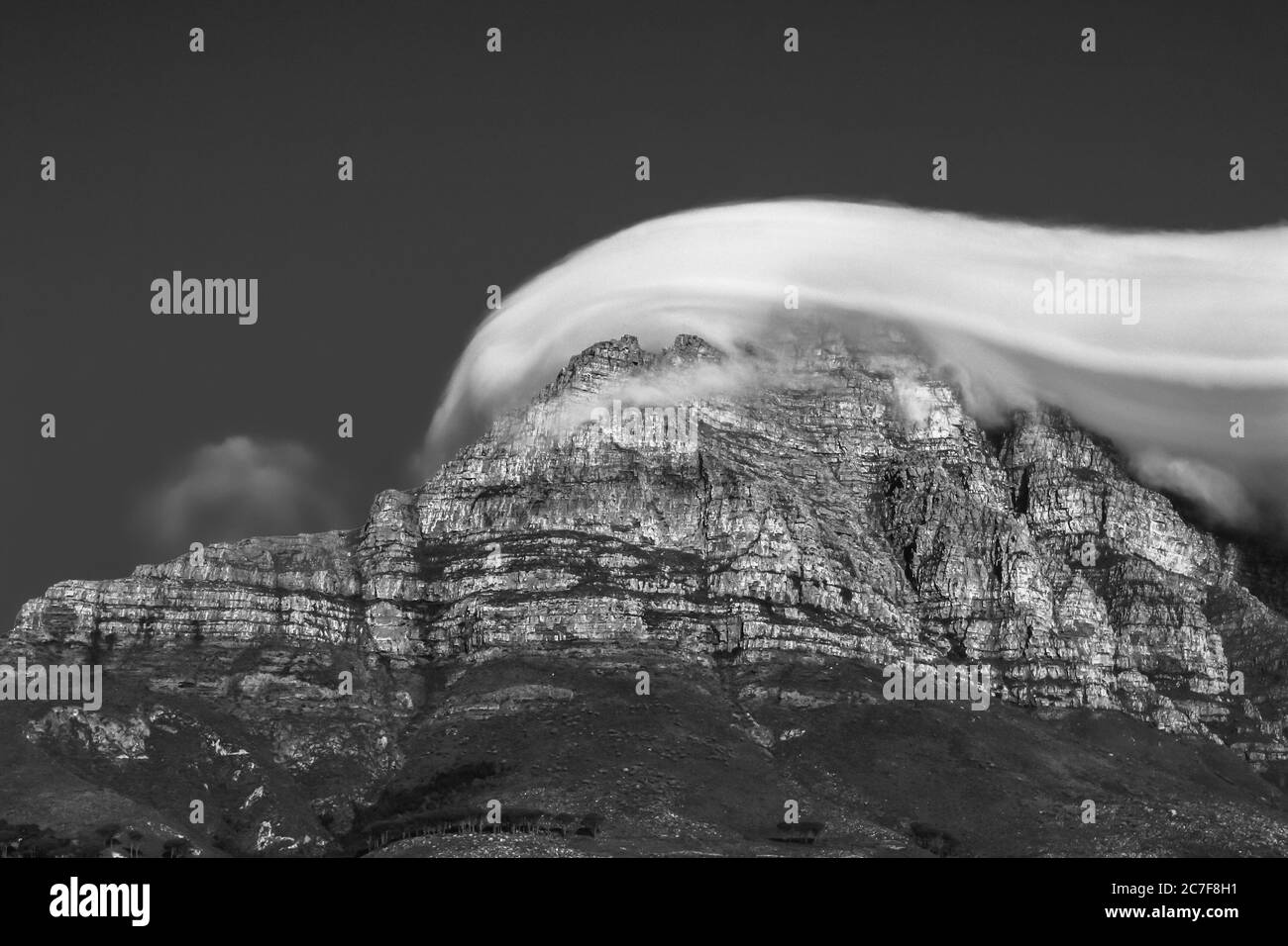 Schöne Graustufen Aufnahme einer felsigen Klippe mit atemberaubenden bedeckt Wolken Stockfoto