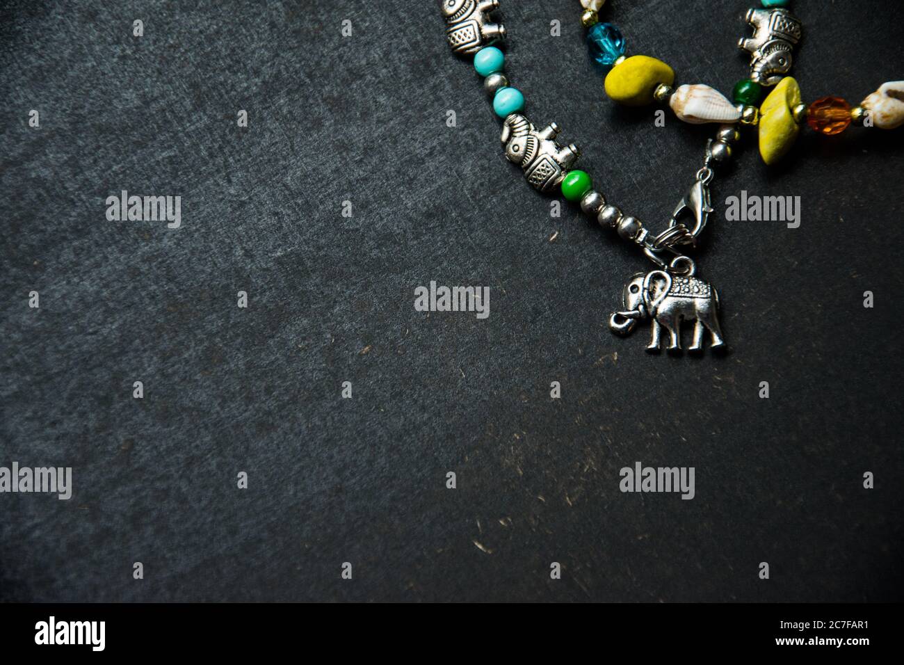 Metallarmband mit einigen Elefanten auf einem dunklen Tisch Stockfoto