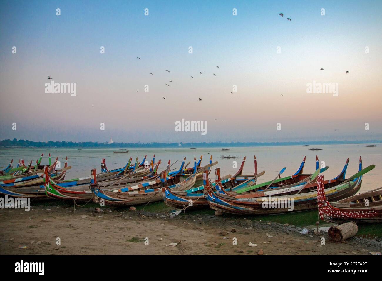 Bunt bemalte Ruderboote Reihen sich am Ufer des Taungthaman Sees in Amarapura, Myanmar an Stockfoto