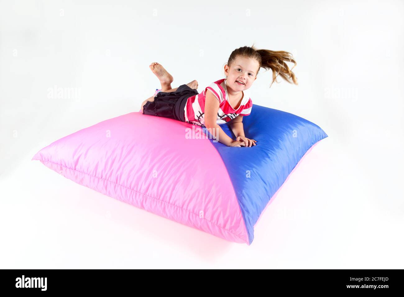 Indoor Spielplatz Mädchen springt auf einem Kissen auf weißem Hintergrund Stockfoto