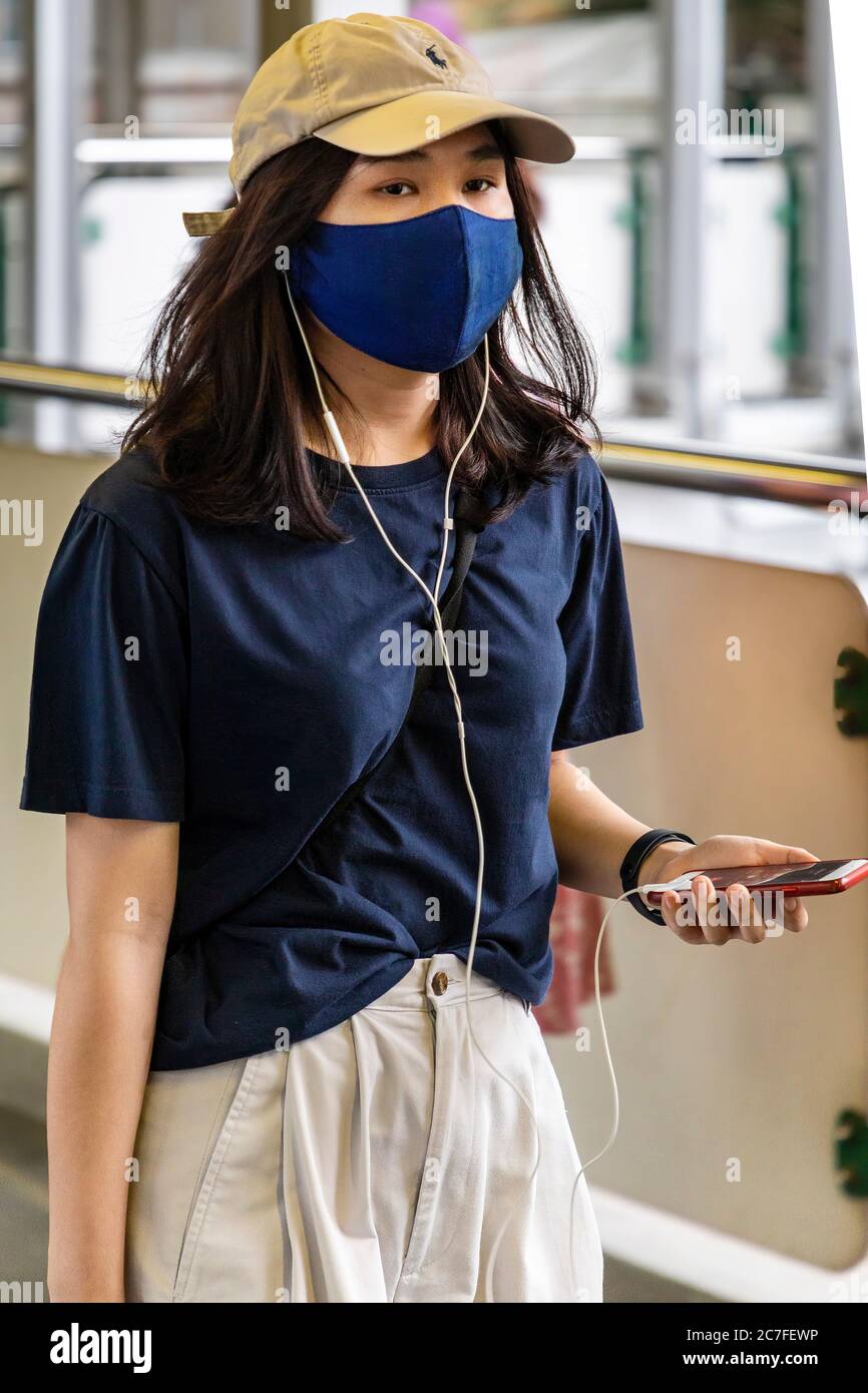 Mädchen trägt Gesichtsmaske und mit Handy während covid 19 Pandemie, Bangkok, Thailand Stockfoto