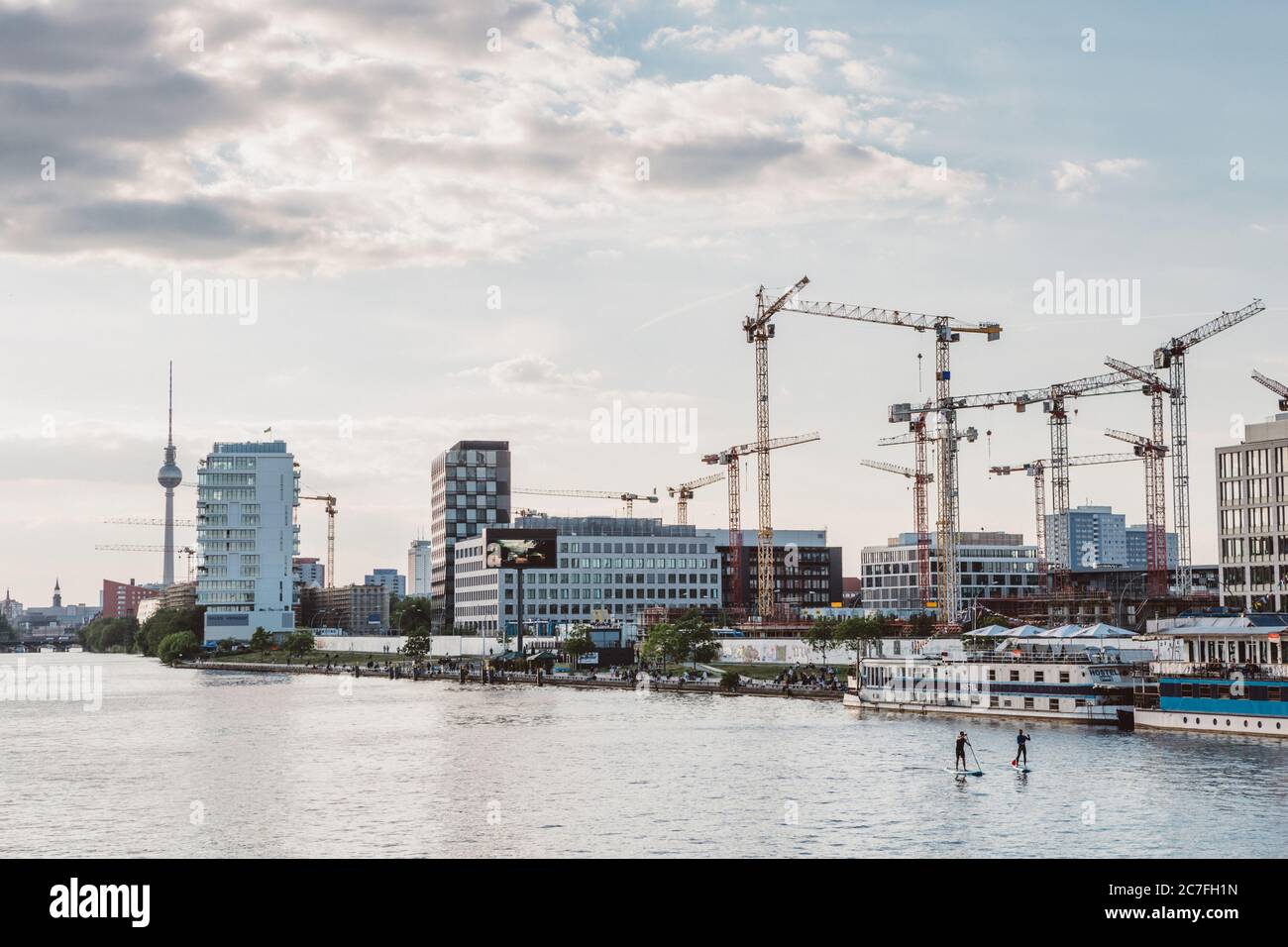 Zwei Jungs verbringen am sonnigen Frühlingstag auf Paddelbrettern auf der Spree in Berlin ihre Freizeit mit fernsehturm im Hintergrund Stockfoto