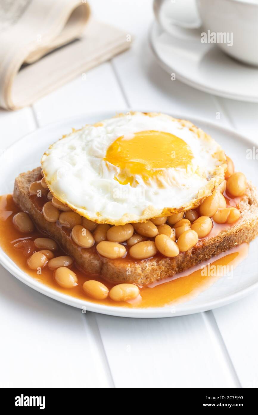 Toast mit Spiegelei und gebackenen Bohnen auf dem Teller. Stockfoto