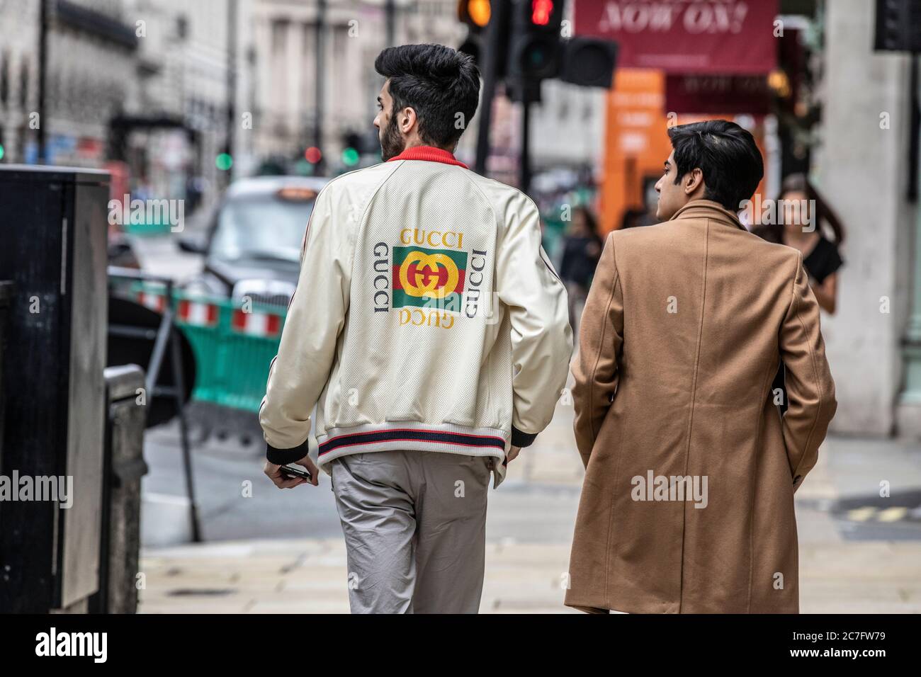 Modische wohlhabende asiatische Männer mit GUCCI-Designer-Bekleidungsmarken, die Piccadilly im West End von London, England, Großbritannien, entlang gehen Stockfoto