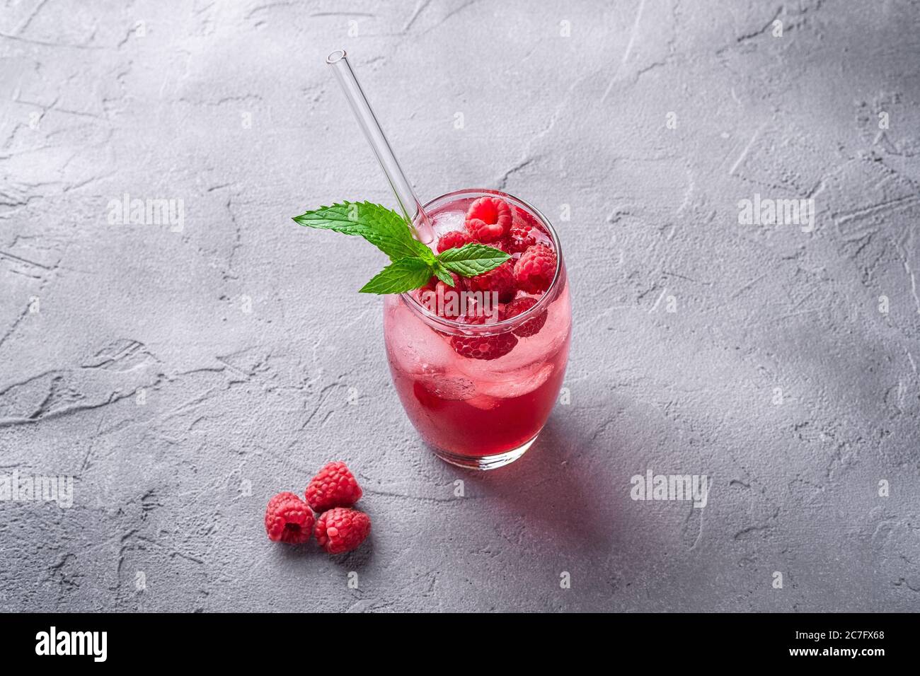 Frisches, eiskalter Beerensaft-Getränk mit Minze, Sommerlimonade aus Himbeer im Glas mit Strohhalmen auf steinbetontem Hintergrund, Winkelansicht Stockfoto