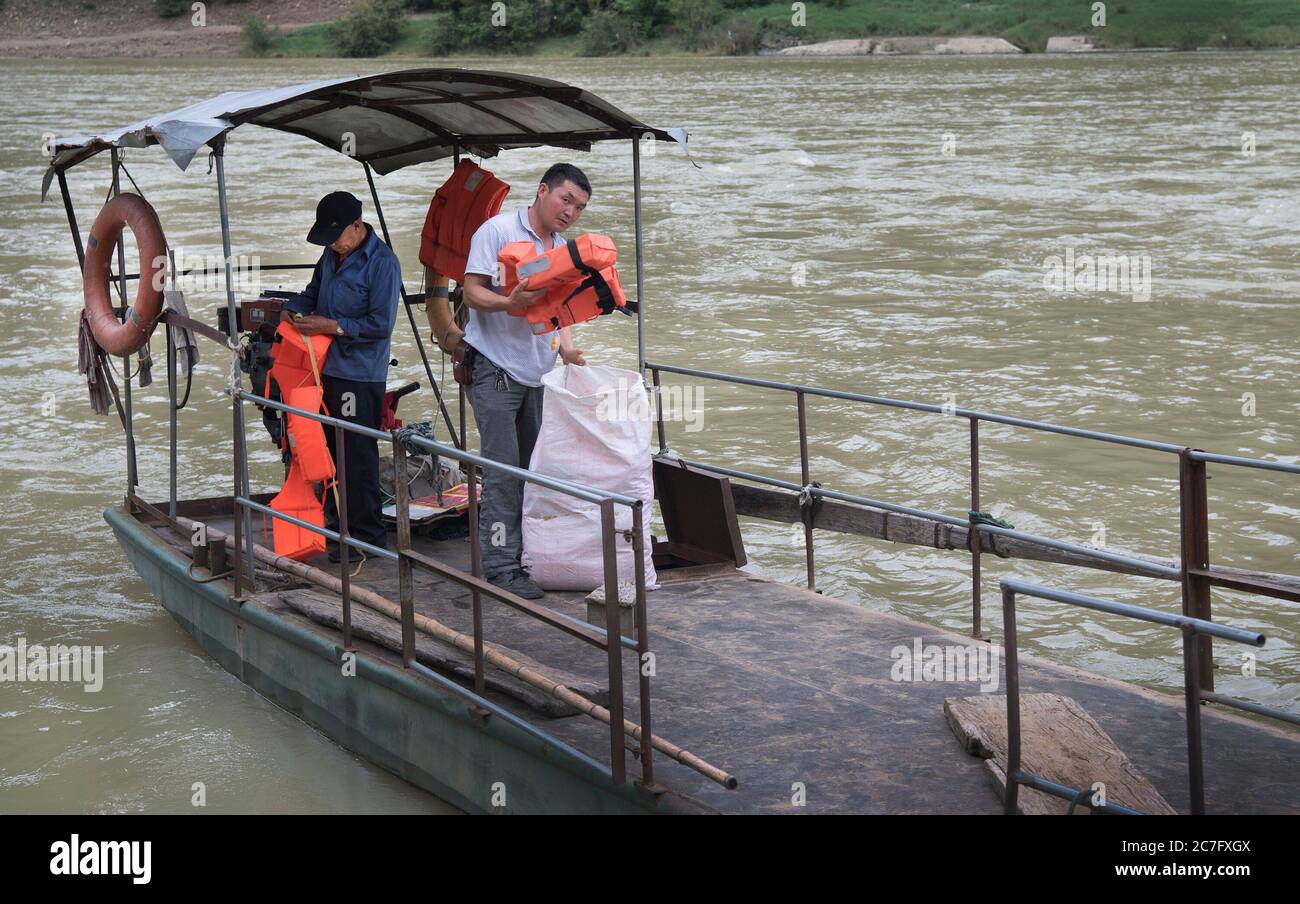 (200717) -- YANGXIAN, 17. Juli 2020 (Xinhua) -- Han Wenxin (L) und Han Baocheng überprüfen die Rettungsanzüge auf dem Boot am Miaoshang in der Stadt Huangjinxia, Stadt Hanzhong in der nordwestlichen chinesischen Provinz Shaanxi, 16. Juli 2020. Han Wenxin, 71, 60 Jahre lang Fährmann am Miaoshang, einem 100 Jahre alten Grenzübergang in der Stadt Huangjinxia, blieb trotz des Wetters und wann immer die Dorfbewohner ihn brauchten, jeden Tag in seiner Position und berechnete kein Geld von seinen verarmten Kunden. 2018 brach Han Wenxin seine Füße und rief seinen Sohn Han Baocheng zurück, um sein Geschäft fortzusetzen. Obwohl e Stockfoto