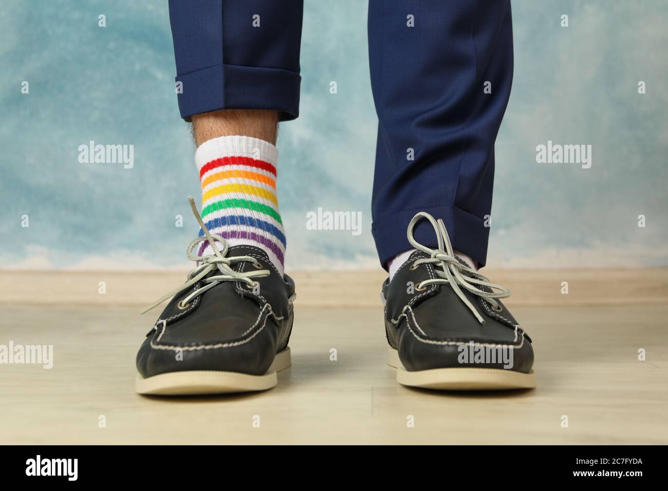Mann in blauer Hose, Slipper und LGBT Socken vor blauem Hintergrund  Stockfotografie - Alamy