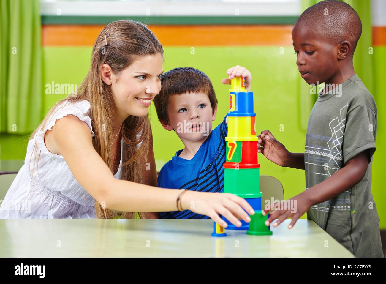 Erzieher spielt mit Jungen im Kindergarten und baut aus Bausteinen einen Turm Stockfoto