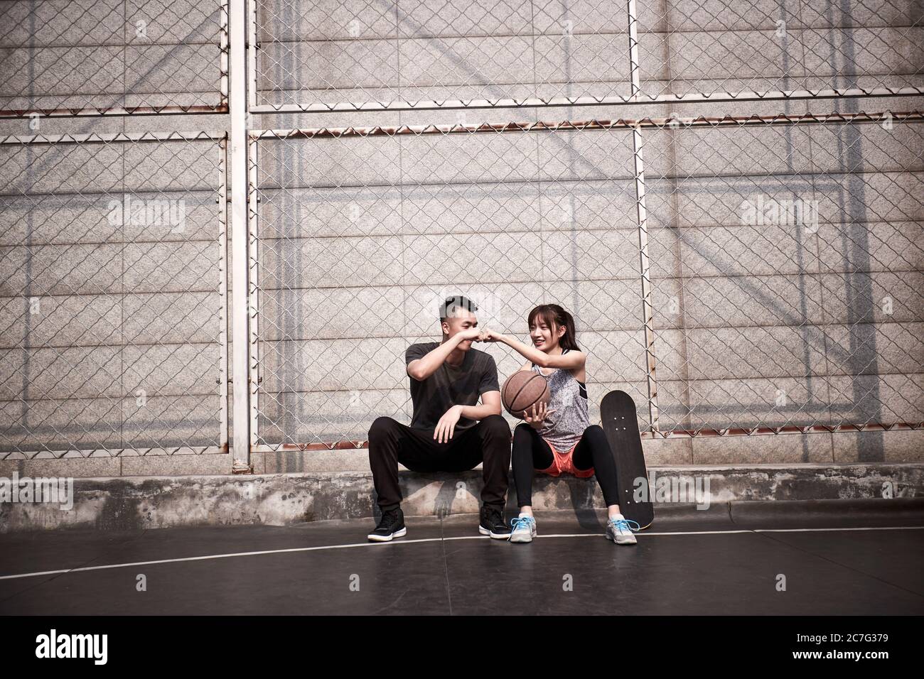 Junge asiatische Erwachsene Mann und Frau stoßen Fäuste auf einem Outdoor-Basketballplatz Stockfoto