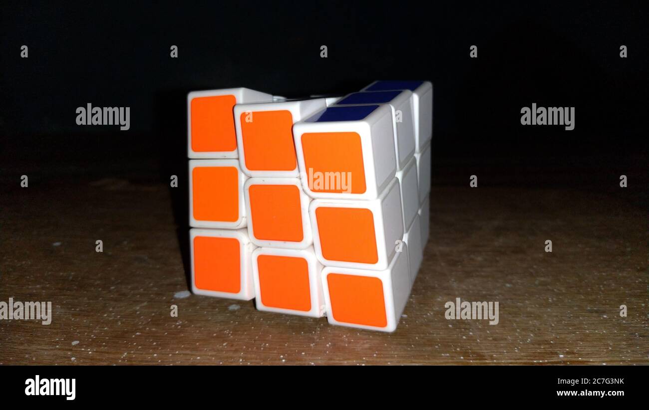 Nahaufnahme eines gelösten Rubik-Würfels auf einem hölzernen Oberfläche mit schwarzem Hintergrund Stockfoto