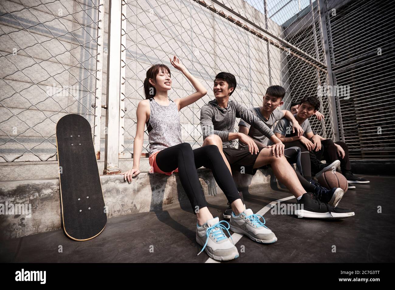 Hipster junge asiatische Erwachsene ruhen sich nach dem Training auf einem Basketballplatz im Freien aus Stockfoto