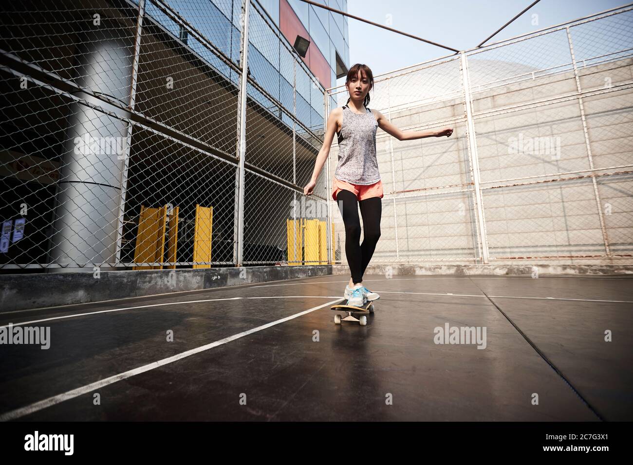 Schöne junge asiatische weibliche Skateboarder üben Skateboarding im Freien Stockfoto