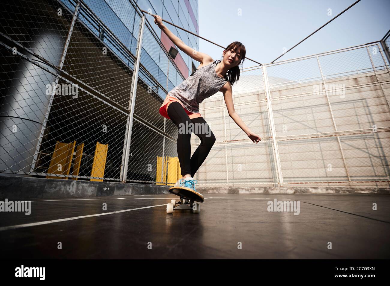 Schöne junge asiatische weibliche Skateboarder üben Skateboarding im Freien Stockfoto