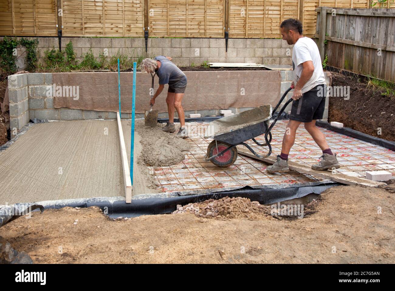 Zwei Bauherren legen einen Betonsockel für ein Gartenstudio Stockfoto