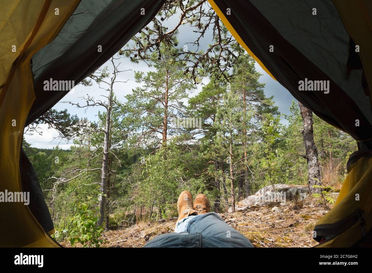 Männliche Stiefel schauen während der Ruhe nach dem Wandern aus dem Zelt. Stockfoto