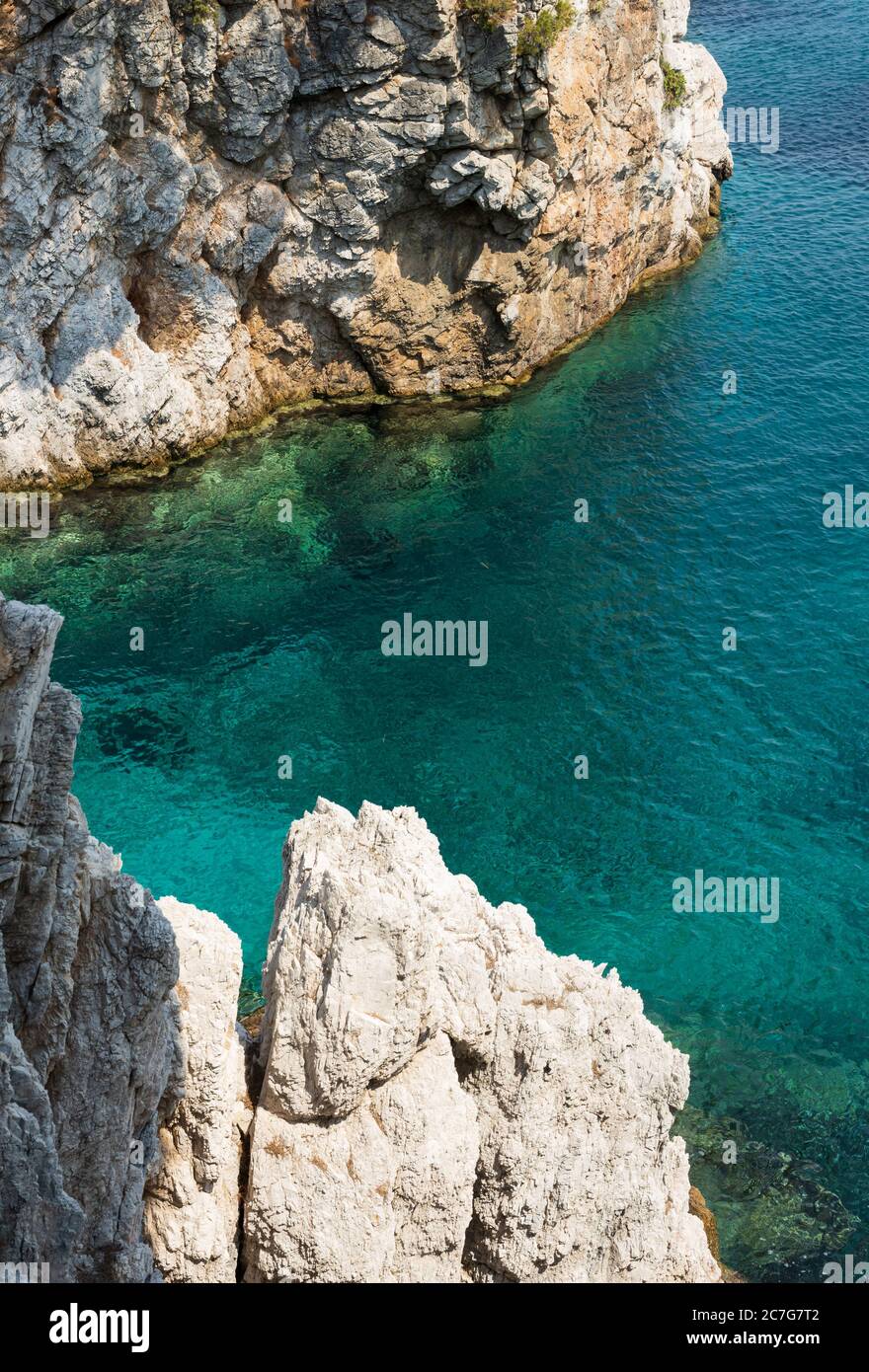 Die Sommersonne lädt das klare, klare, blaue und türkisfarbene Wasser zum Leuchten in einer Bucht der Insel Skopelos ein und Sie wollen sich zur Erfrischung einlassen. Stockfoto