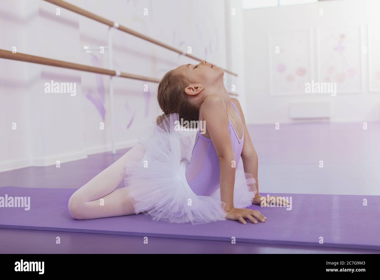 Junge Ballerina Mädchen Ausübung bei Ballettklasse. Niedliche kleine Ballerina Mädchen Stretching bei Ballettschule. Gymnastik, Flexibilität, aktive Kinder Konz Stockfoto