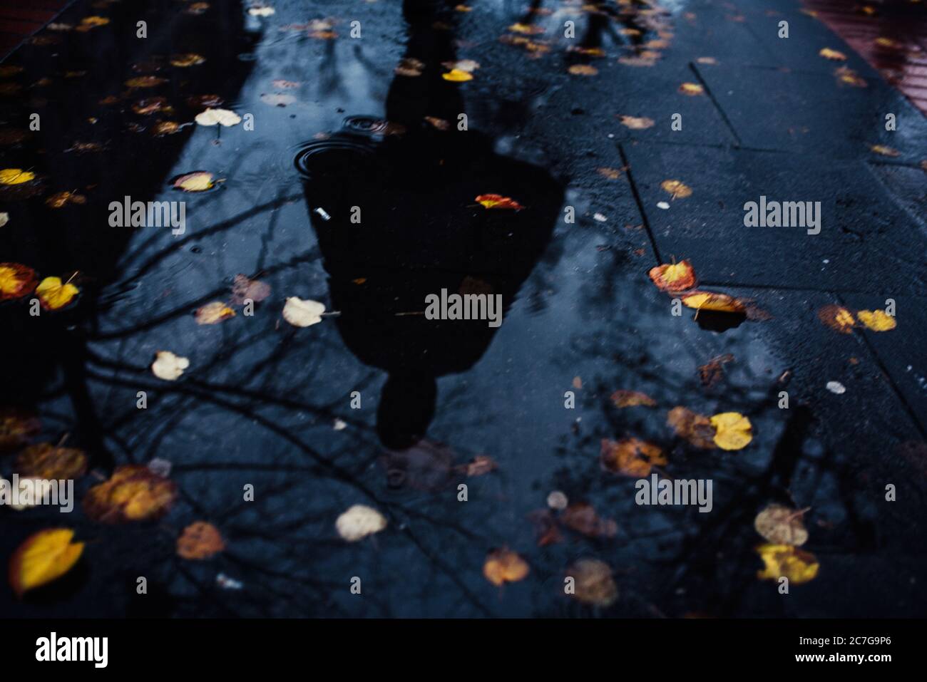Reflexion einer Person in einer Pfütze von Wasser unter Der Regen Stockfoto