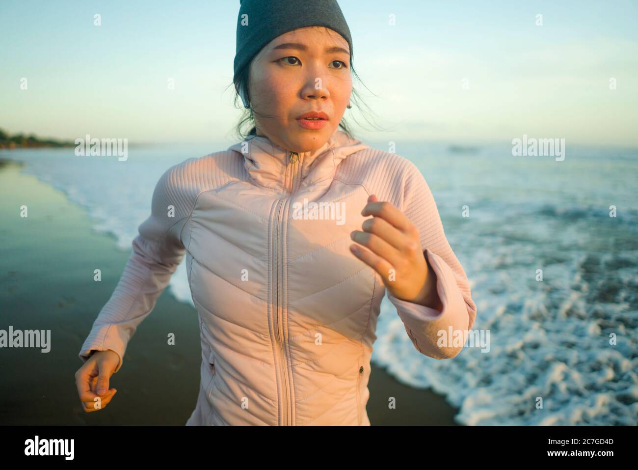 Asiatische Mädchen am Strand laufen - junge attraktive und glückliche koreanische Frau tun Jogging-Training am schönen Strand genießen Fitness und gesunde Läufer Stockfoto