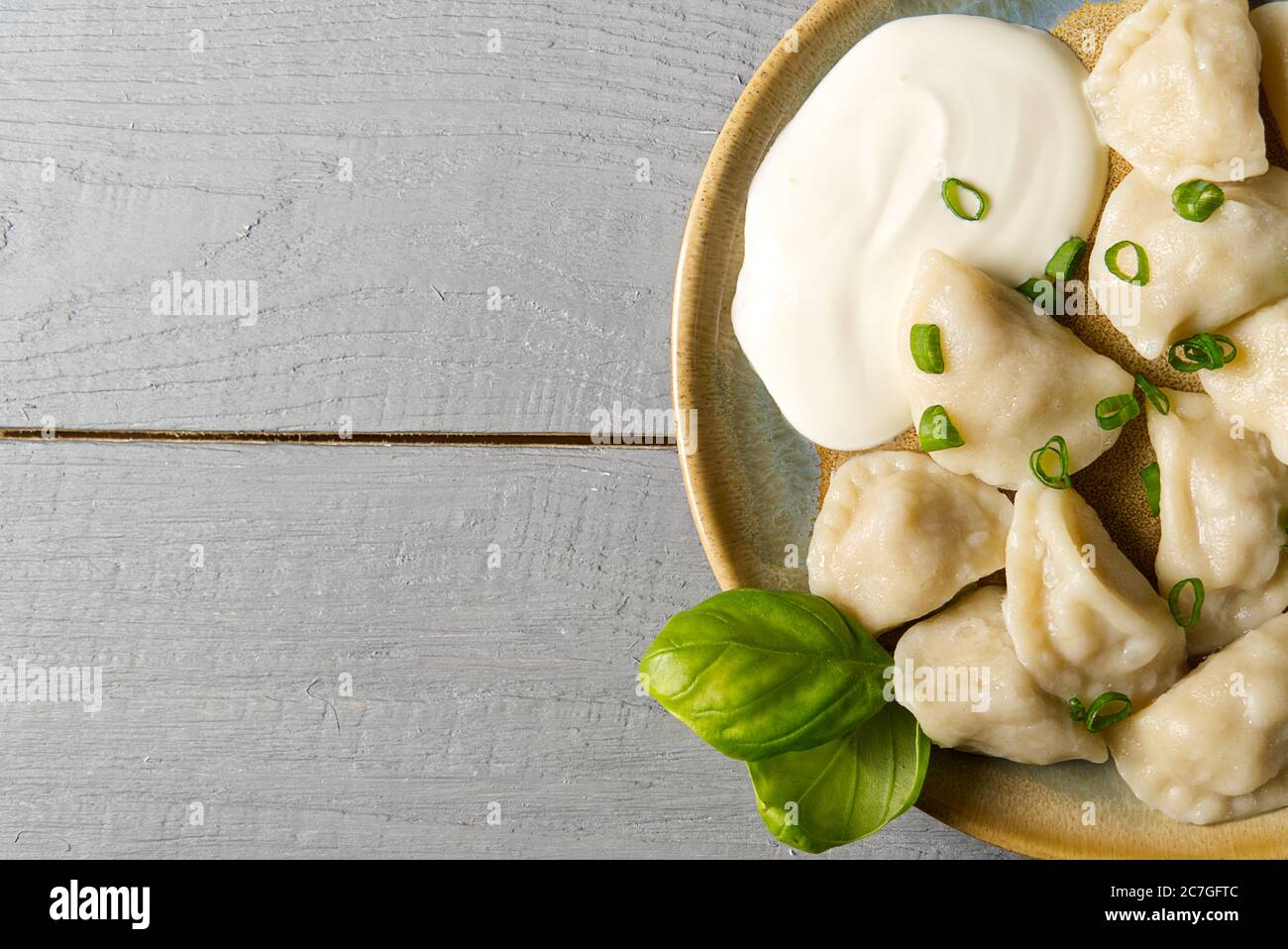 Frisch gekochte Fleischknödel mit saurer Sahne auf Holzgrund serviert. Stockfoto