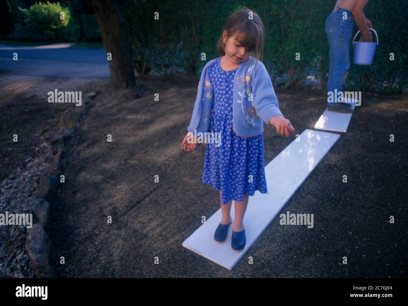 Junges Mädchen, das Vater beim Aussaaten von Grassamen im Garten unterstützt, das auf Einer Waldplanke steht Stockfoto