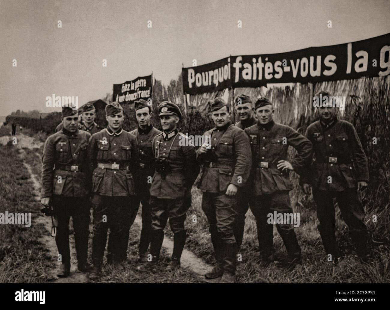 Nach der Schlacht um Frankreich, auch bekannt als der Fall Frankreichs, der deutschen Invasion Frankreichs und der Niederlande im Frühjahr 1940 während des Zweiten Weltkriegs, steht eine Gruppe deutscher Soldaten vor Propagandaplakaten. Stockfoto
