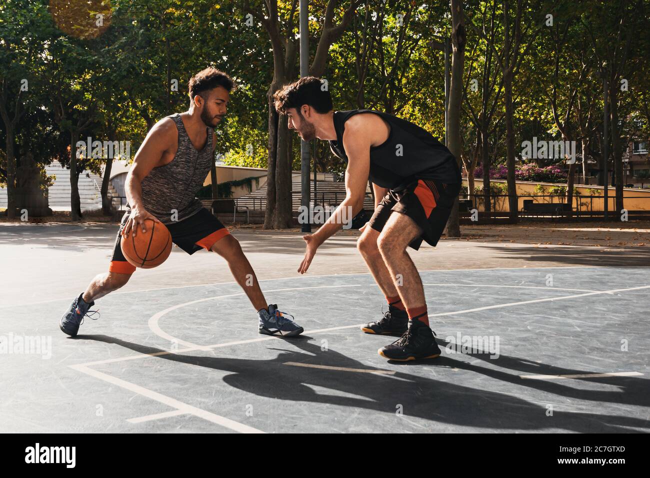 Zwei junge Männer spielen Basketball im Freien kämpfen um den Ball Stockfoto