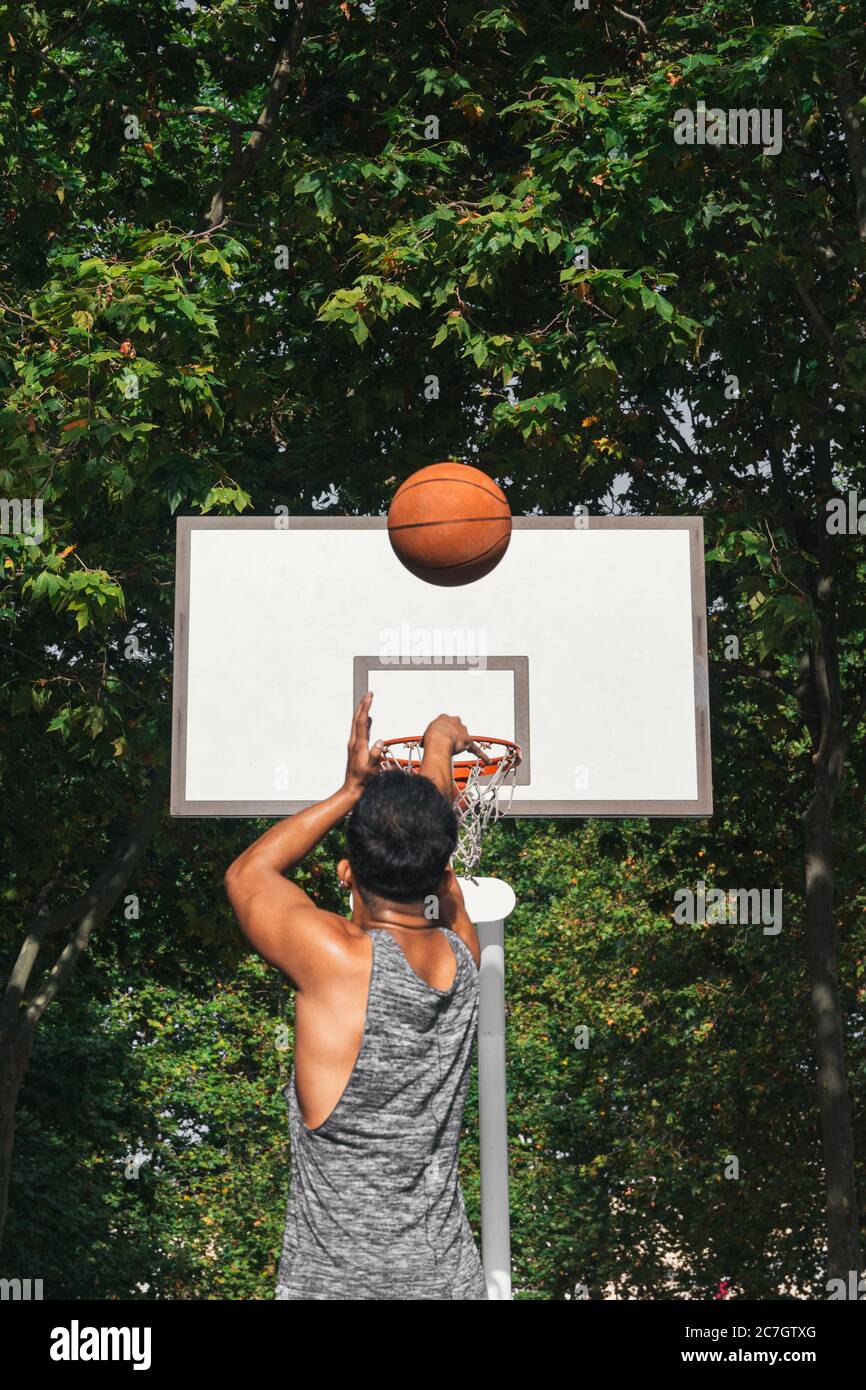 Junger Mann vor dem Korb, der den Ball wirft Stockfoto