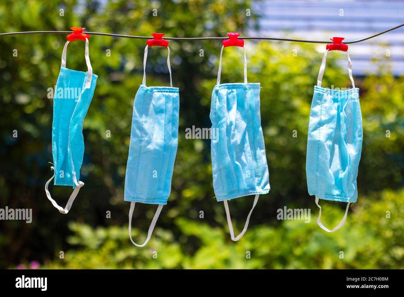 Selektive Fokussierung von Gesichtsmasken, die nach dem Waschen an einem Draht hängen. Stockfoto