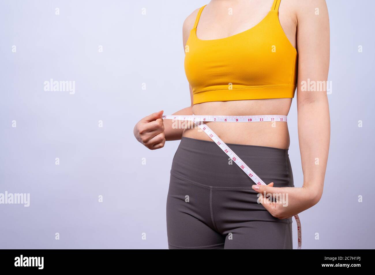 Asiatische sportliche Frau Messung ihre Taille durch Maßband isoliert Auf weißem Hintergrund Konzept eines gesunden Lebensstils Stockfoto