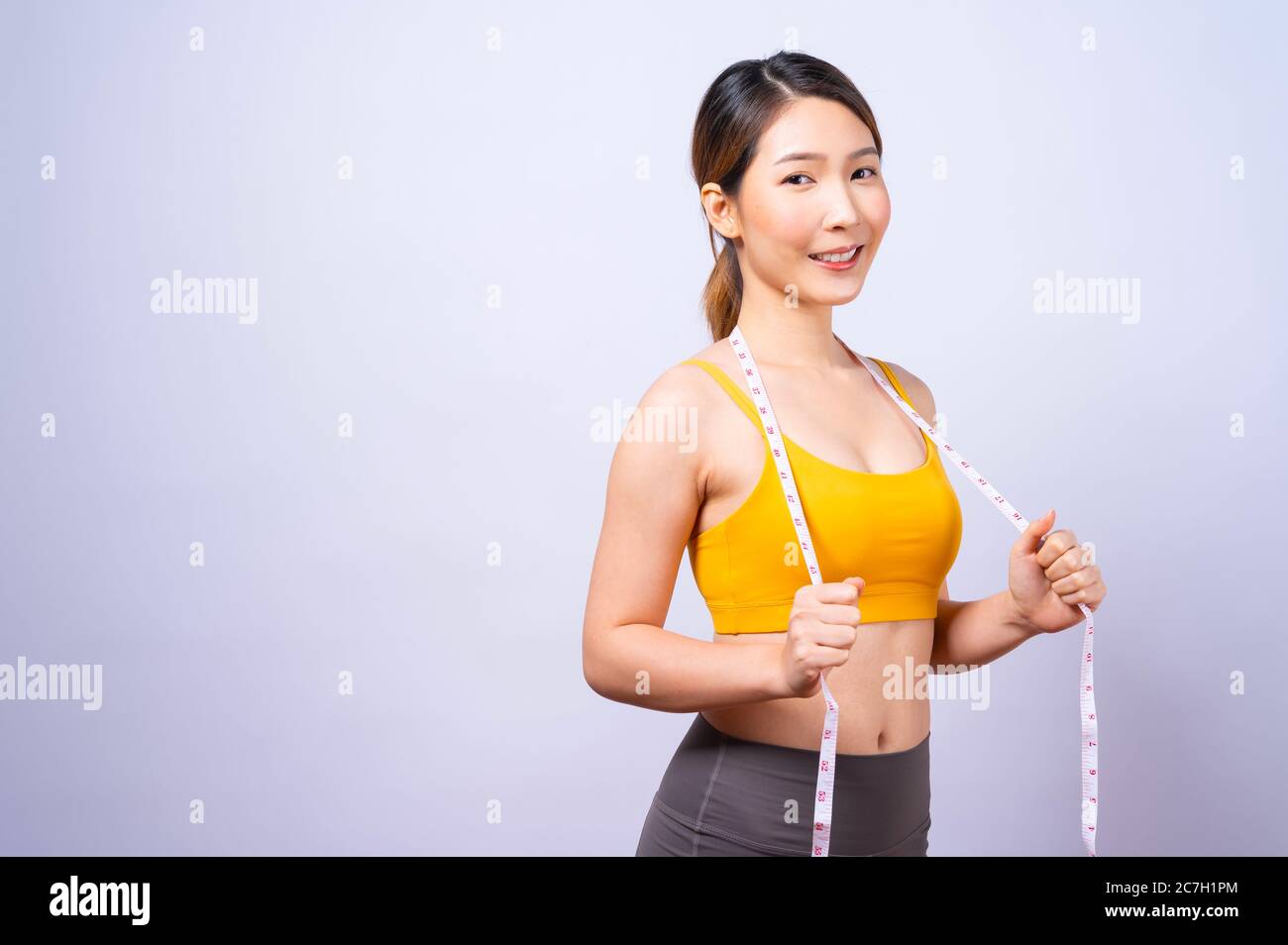 Asiatische sportliche Frau Messung ihre Taille durch Maßband isoliert Auf weißem Hintergrund Konzept eines gesunden Lebensstils Stockfoto
