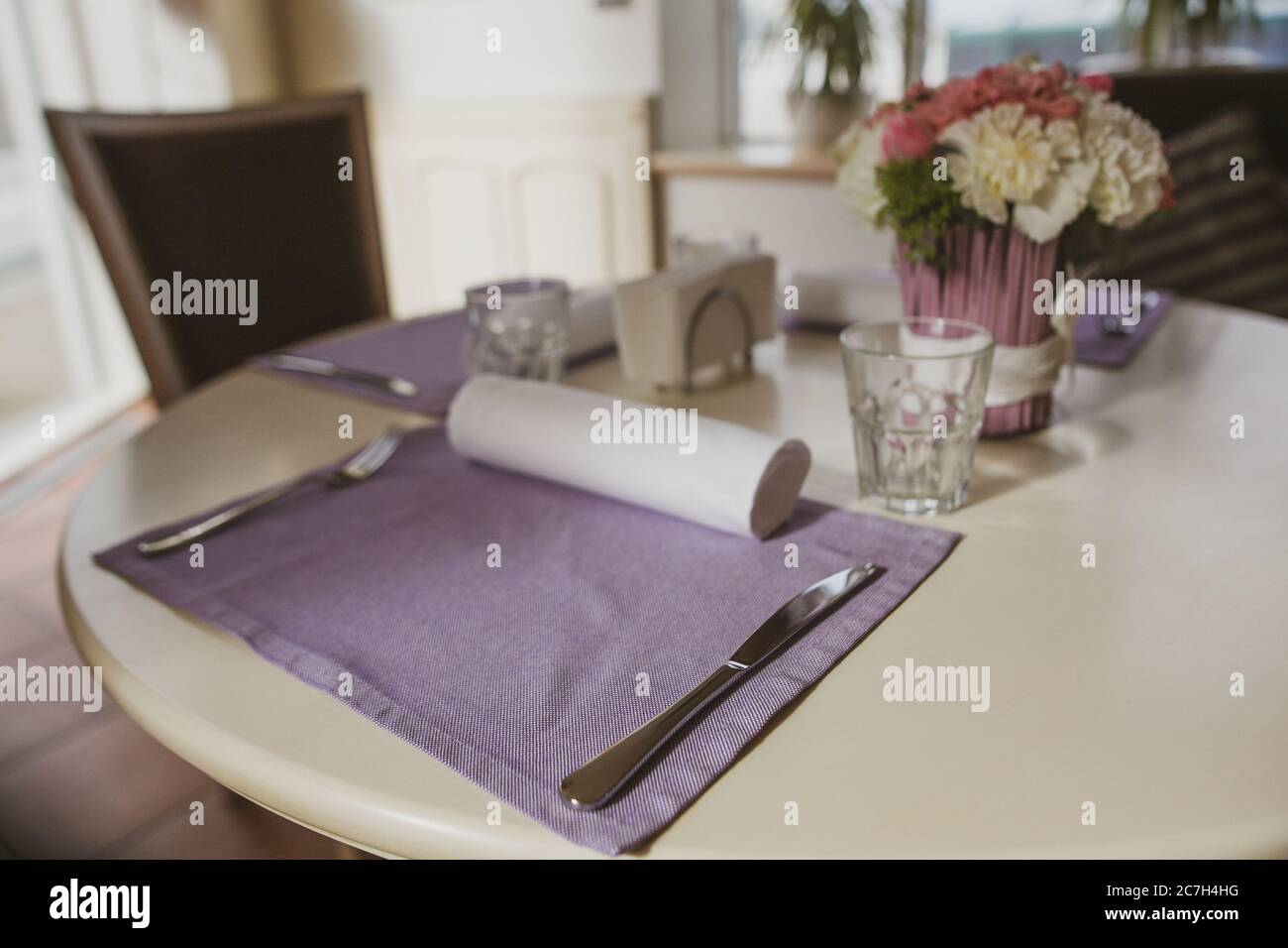 Bankettsaal mit Blumen. Helle Einrichtung auf dem runden Tisch mit Rosenstrauß im Haus oder Restaurant. Tischdeko-Konzept Stockfoto