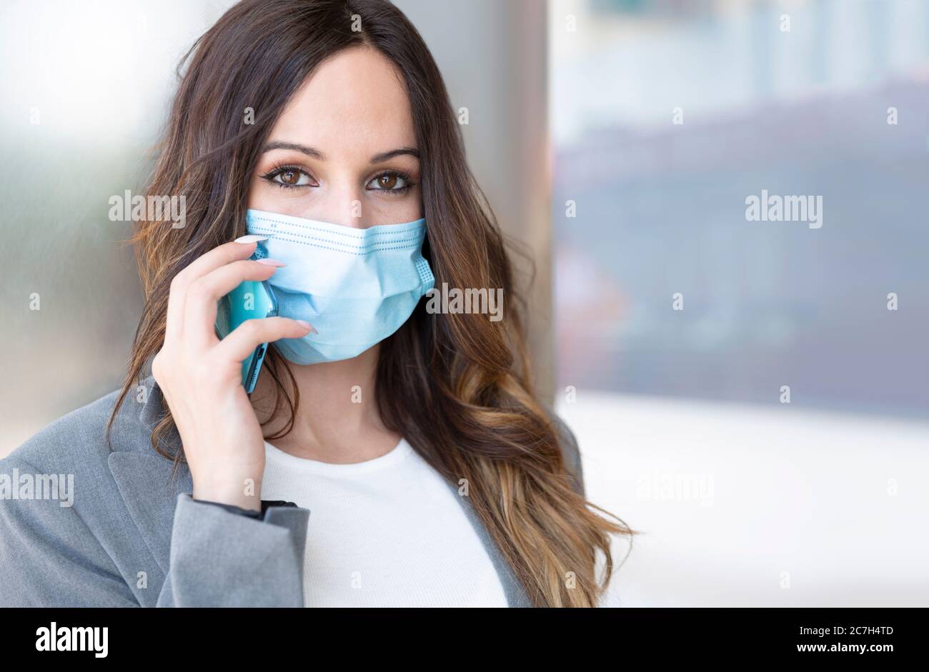 Nahaufnahme einer jungen Unternehmerin, die über ihr Smartphone spricht. Sie trägt eine Gesichtsmaske. Selektiver Fokus. Leerzeichen für Text. Business und New Stockfoto